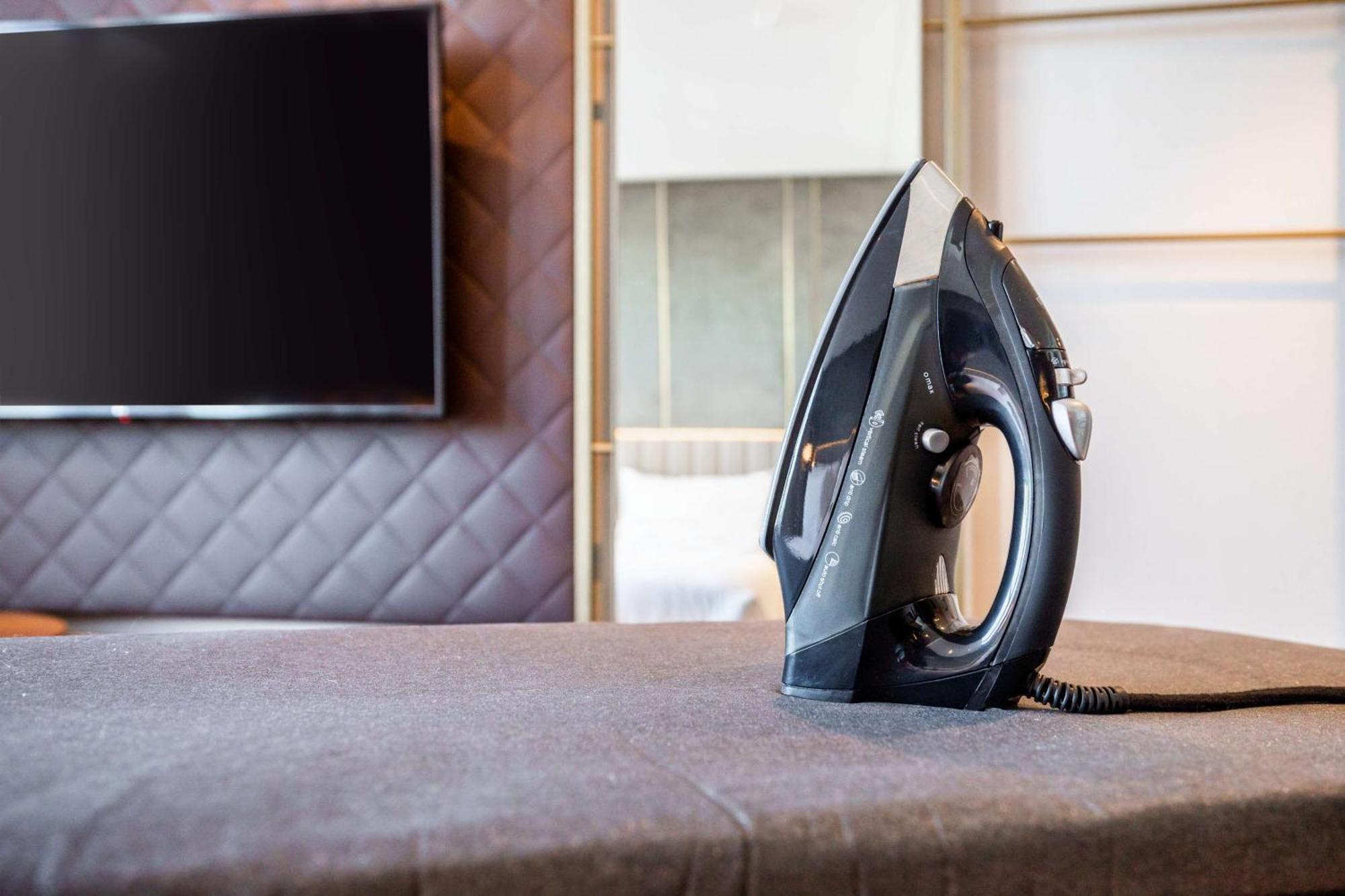 Nh Collection Copenhagen Hotel Luaran gambar The photo shows a black iron placed on a grey ironing board, which is covered with a fabric surface. In the background, there's a large television mounted on the wall, and the setting appears to be a modern room with stylish decor, featuring a quilte